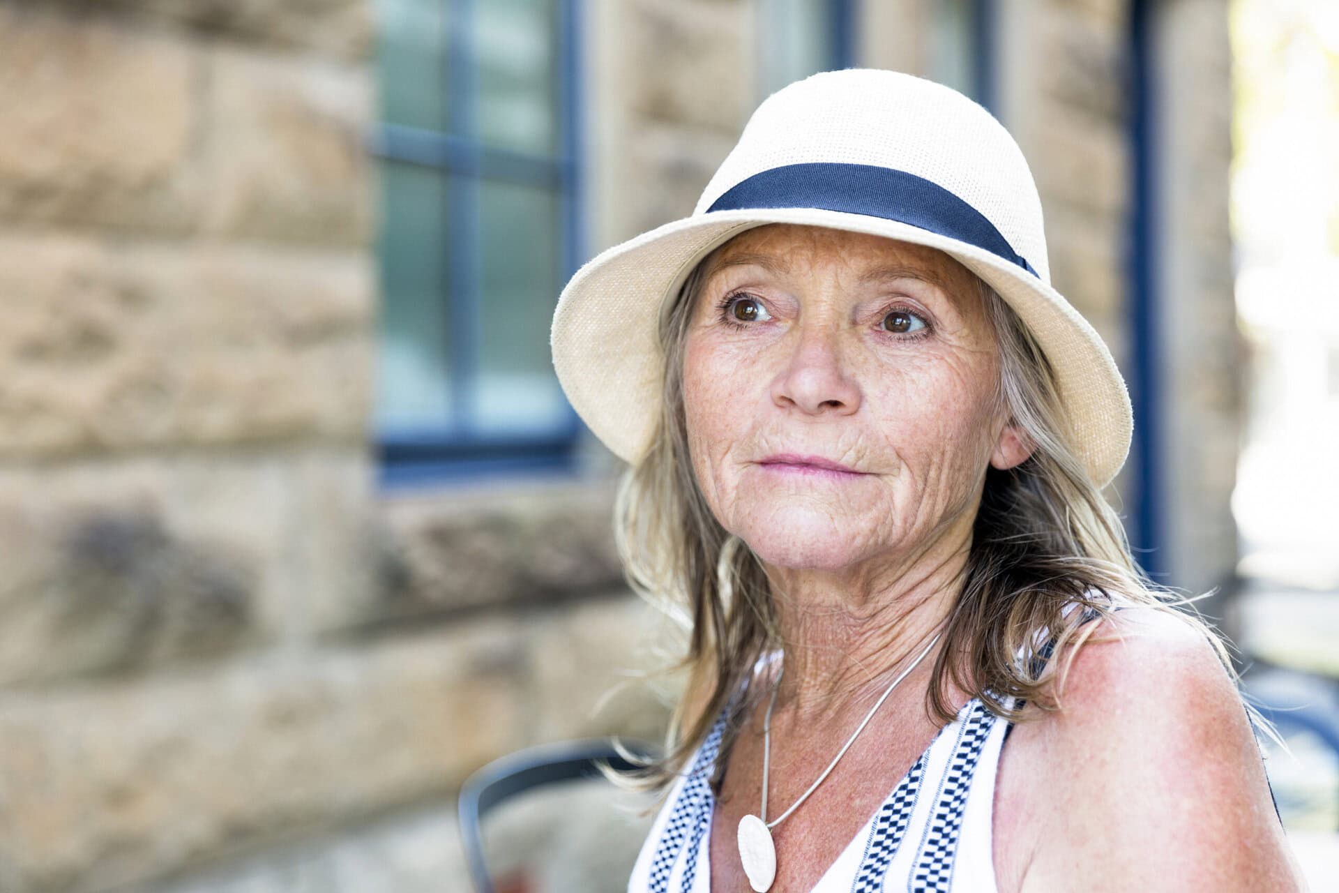 Ältere Frau mit hellem Sommerhut im Freien